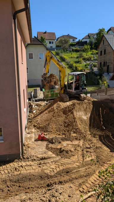 Bagger beim Aushub einer Baugrube in Linz-Land für Gebäudevergrößerung