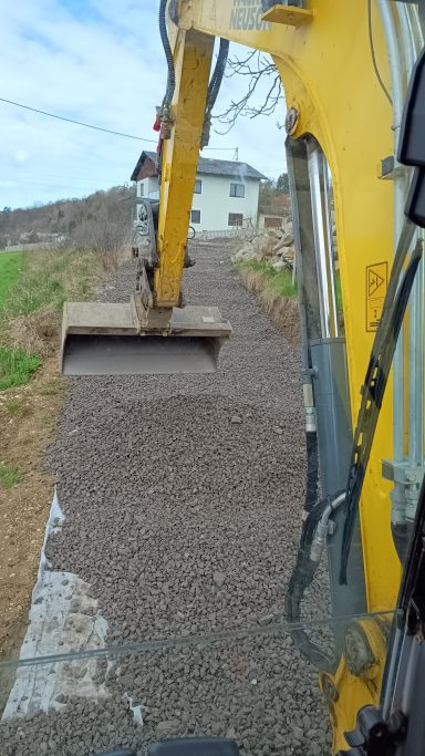 Bagger verteilt Granitbruch beim Wegebau in Feldkirchen an der Donau