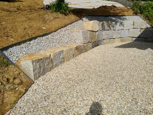 Gartengestaltung Steinschlichtung mit Rasenkante und Sitzplatz in Altenfelden, Stützmauer aus Naturstein