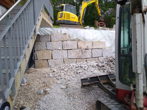 Steinschlichtung mit Kettenbagger bei Parkfläche in Wilhering, Naturstein als Böschungssicherung gesetzt.